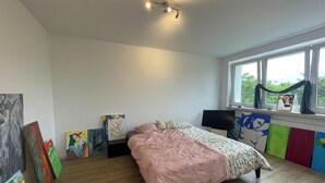 Una camera da letto con un letto, una televisione, opere d'arte alle pareti e una finestra con tende.