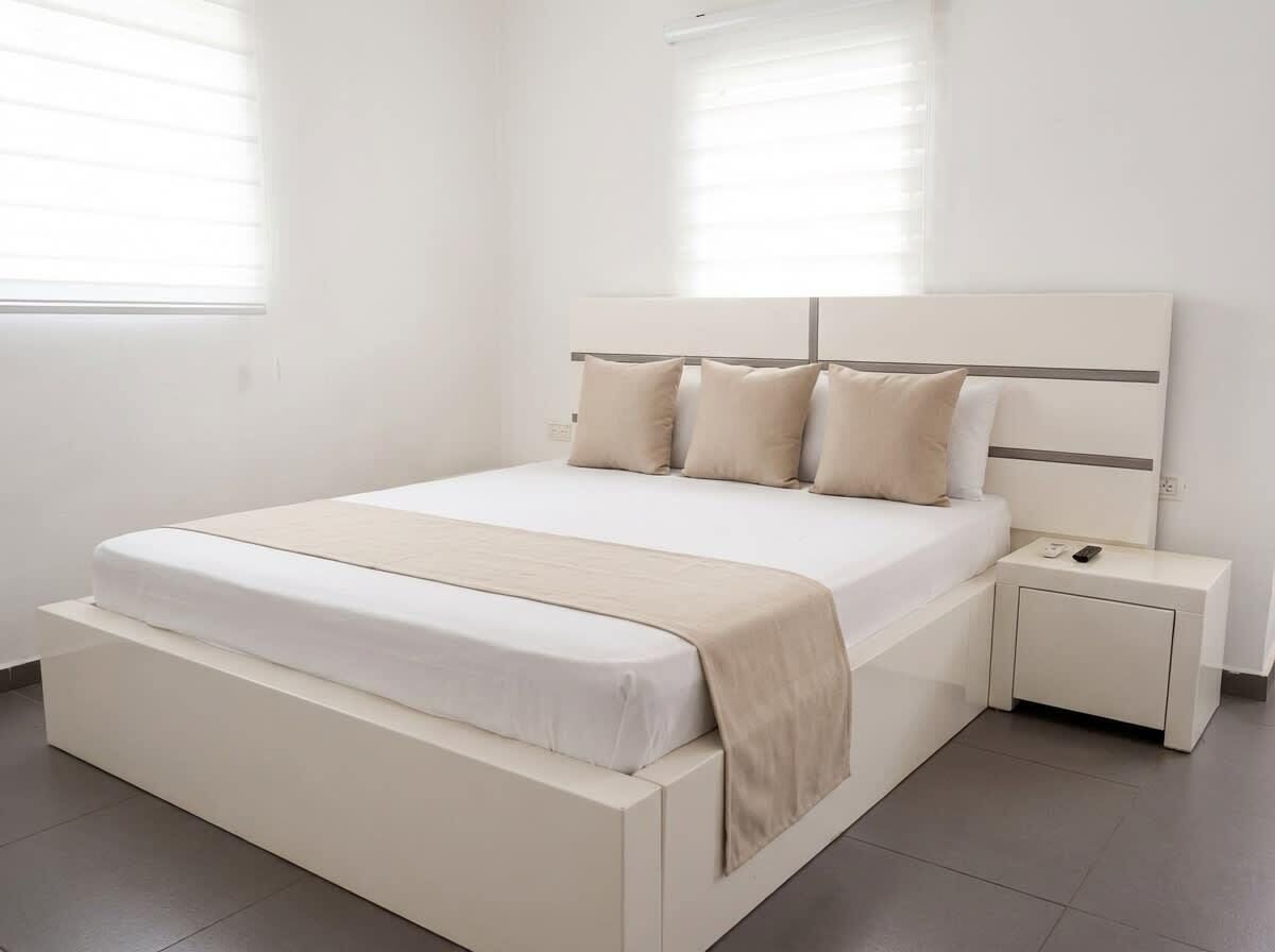 A modern bedroom with a large bed, a bedside table, and a nightstand.