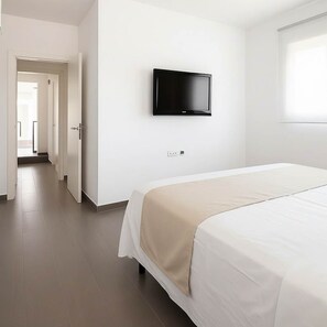 Ein Hotelzimmer mit Bett, Wandfernseher und Blick auf den Flur.