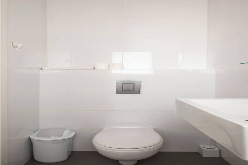 Ein Badezimmer mit Toilette, Mülleimer, Handtuchhalter und einer weißen Badewanne.