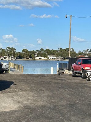 Ein Parkplatz am Wasser mit einem roten Pickup, einem weißen Transporter und einem angedockten Boot.