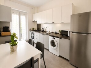 Una cocina moderna con electrodomésticos de acero inoxidable, horno empotrado, microondas y lavadora.