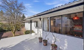 Una casa moderna con amplios ventanales, fachada blanca y plantas en macetas en el porche.