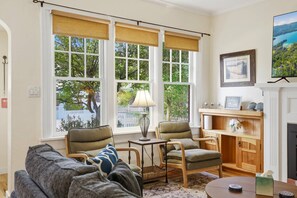 A living room with a sofa, two armchairs, a small table, and a fireplace. - Charming Cottage in Coeur d'Alene | Steps from North Idaho College and Downtown CDA |Private Hot Tub (Coeur d'Alene)