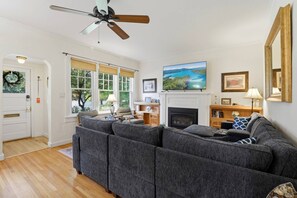 Un salon comprenant un canapé d’angle, une cheminée, un téléviseur et un ventilateur de plafond.