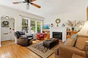 Ein Wohnzimmer mit Kamin, Ledersofas, Fernseher und Bücherregal.