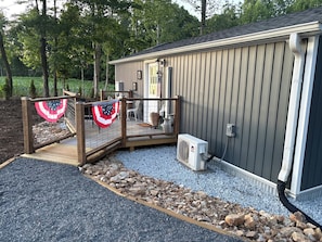 A covered outdoor area with a wooden deck, a grill, and a flag.