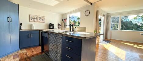 A modern kitchen with blue cabinets, a central island, and a large window providing natural light.