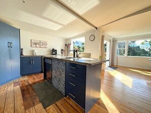 A modern kitchen with blue cabinets, a central island, and a large window providing natural light.