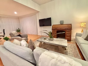 A living room with a sofa set, a coffee table, a fireplace, a TV, and a lamp.
