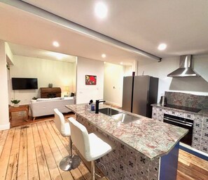 A modern kitchen with a marble countertop, a built-in sink, and a stainless steel range hood.