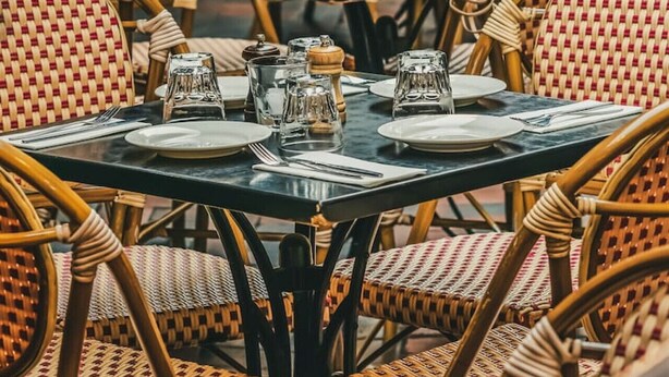 A dining area with wicker chairs and tables, each set with plates, cutlery, and salt and pepper shakers. - Evi-3B2B Free Parking! Walk to Casino! Sleeps 8! (Southbank)