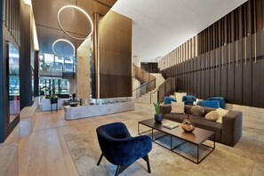 Eine moderne Lobby mit einer geschwungenen Treppe, einer Sitzecke mit Sofa und Sesseln sowie einem Couchtisch.