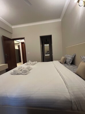 Ein Hotelzimmer mit einem großen Bett, einer Tür, einem Spiegel und einem Nachttisch.