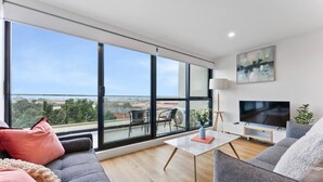 Ein modernes Wohnzimmer mit großem Fenster, Flachbildfernseher und einer Couch.
