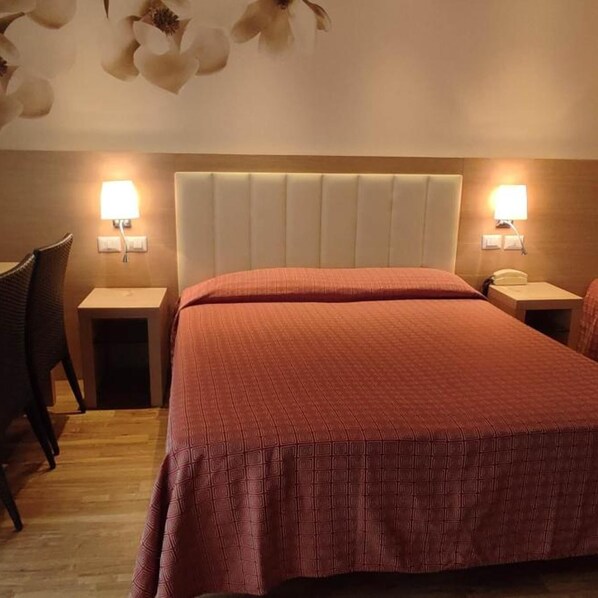 A hotel room with a bed, two bedside tables, a chair, and a wall-mounted lamp. - Hotel San Remo (Riccione)