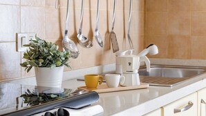 Una cucina con un piano di lavoro bianco, una macchina per il caffè, una pianta e utensili appesi al muro.