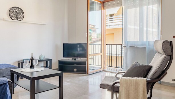 Un soggiorno moderno con una TV, un tavolo da pranzo, un divano e una poltrona.