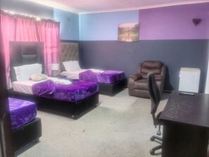 Ein Zimmer mit zwei Betten, einem Sessel, einem Schreibtisch und einem kleinen Schrank.