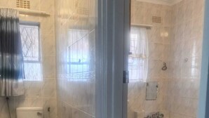 Kylpyhuone, jossa on wc, suihkukaappi ja kylpyamme.
