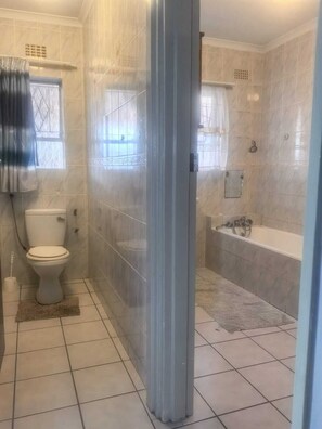 Et badeværelse med toilet, bruseniche og badekar.