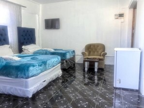 Ein Zimmer mit zwei Betten, einem Sessel, einem kleinen Tisch und einem weißen Schrank.
