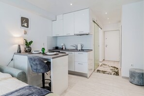 Una cocina compacta con armarios blancos, una pequeña isla y un taburete de bar.