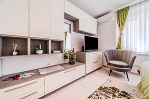 A modern living room with a flat-screen TV, a sofa, a coffee table, and a dining area with a table and chairs. - Zagreb City Center Vibes Near Main Square (Zagreb)
