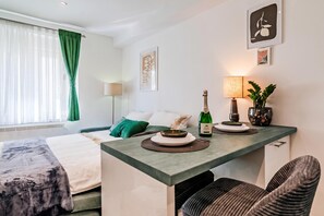 A hotel room with a bed, a small table with a bottle of champagne, a lamp, and a potted plant. - Zagreb City Center Vibes Near Main Square (Zagreb)