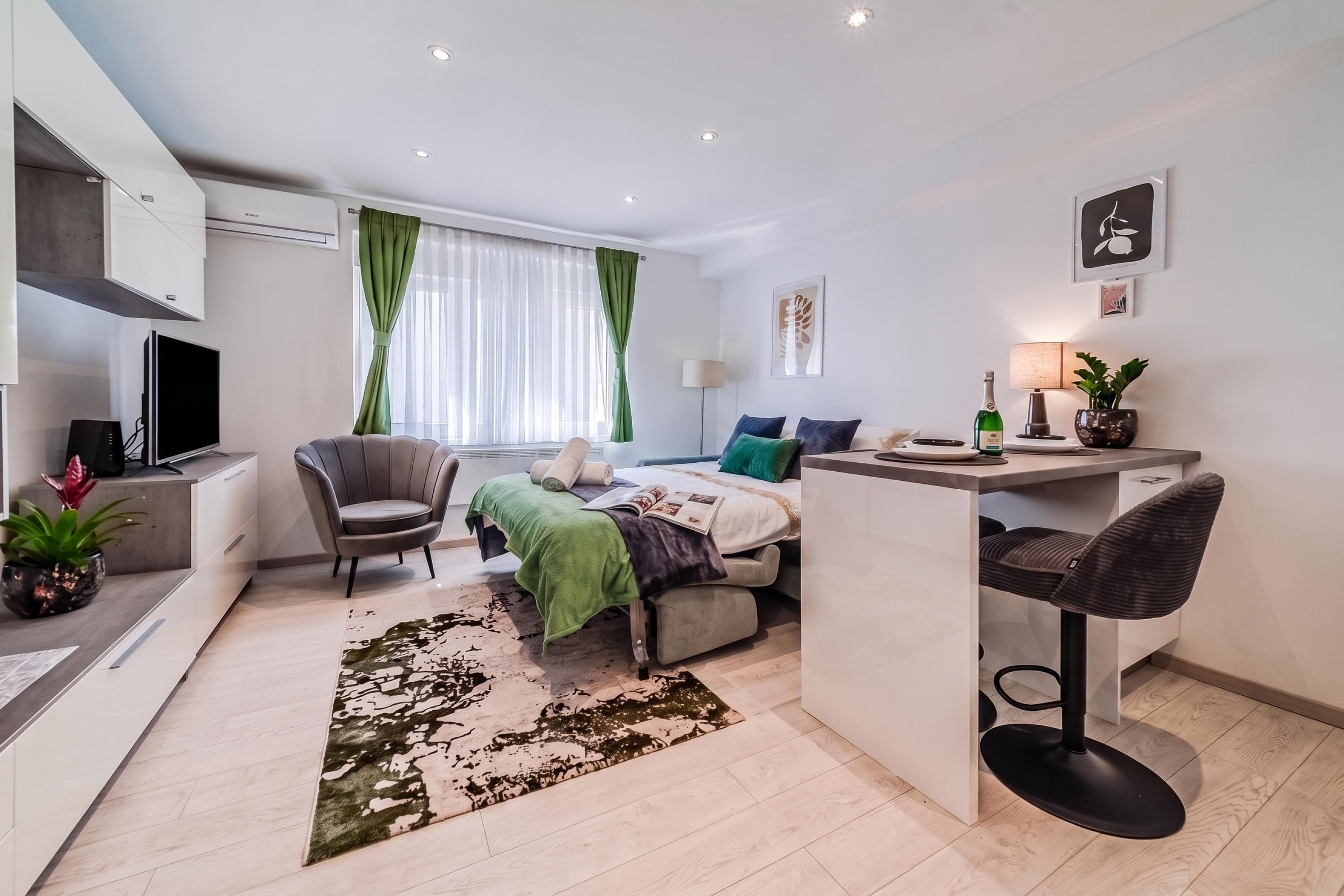 Una habitación moderna y bien iluminada con una cama, un escritorio, una silla y un televisor.