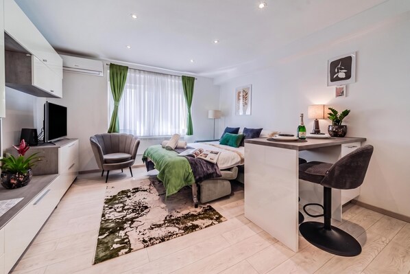 Ein modernes, helles Zimmer mit einem Bett, einem Schreibtisch, einem Stuhl und einem Fernseher.