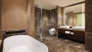 A modern bathroom with a freestanding bathtub, a glass-enclosed shower, and a vanity with two sinks. - Courtyard Shillong (Shillong)