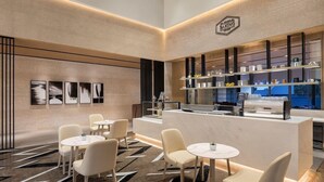 A modern cafe with a marble floor, white chairs, and a counter with various items. - Courtyard Shillong (Shillong)
