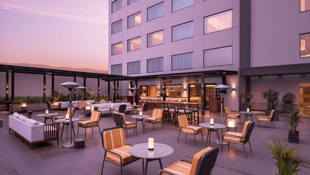 A rooftop bar with outdoor seating, including sofas and chairs, and a bar area with a counter. - Courtyard Shillong (Shillong)