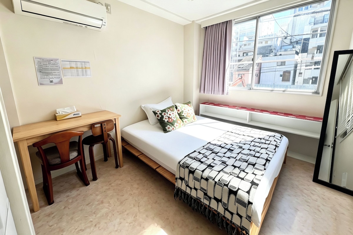 A compact bedroom with a single bed, a desk, and a chair.