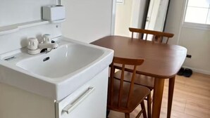 A kitchenette with a sink, a small countertop, and a cabinet. There is a wooden dining table with four chairs.