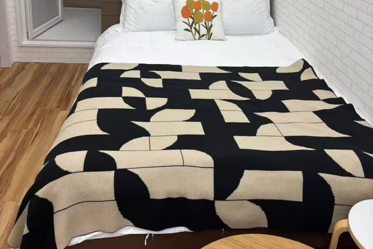 Un dormitorio con cama, cabecero de madera, pared de ladrillo blanco y suelo de madera.