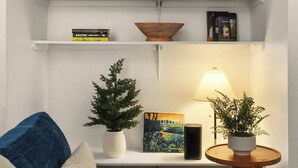 A modern living room with a blue sofa, white shelves, and a small wooden table with a lamp. - Walk to UT Austin - 6 Min to Downtown (Austin)