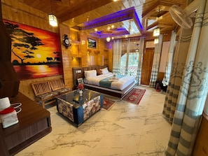 A wooden interior with a bed, a bench, a table, and a painting.