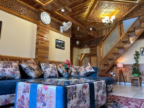 A cozy living room with a sofa, a clock, and a staircase.