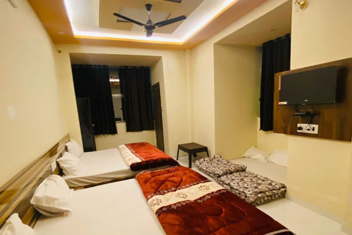 Habitación de hotel con un diseño moderno en el techo, un televisor de pantalla plana en la pared y una cama con una manta roja.