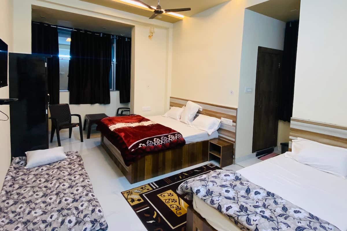 Une chambre d’hôtel avec deux lits simples, un ventilateur de plafond, une télévision et un petit bureau.
