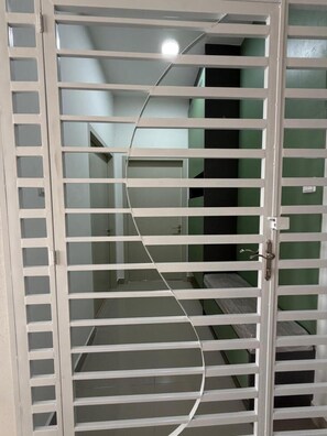 Ein Zimmer mit weißer Tür, einem Spiegel und einer grünen Wand.