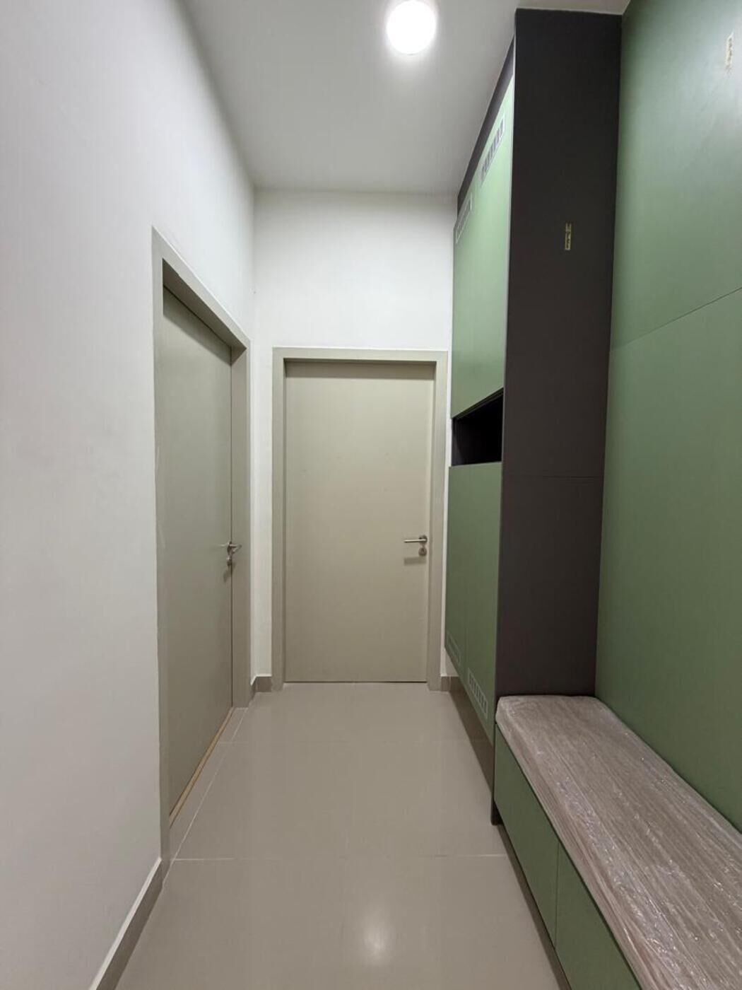 A hallway with a bench, a door, and a green wall.