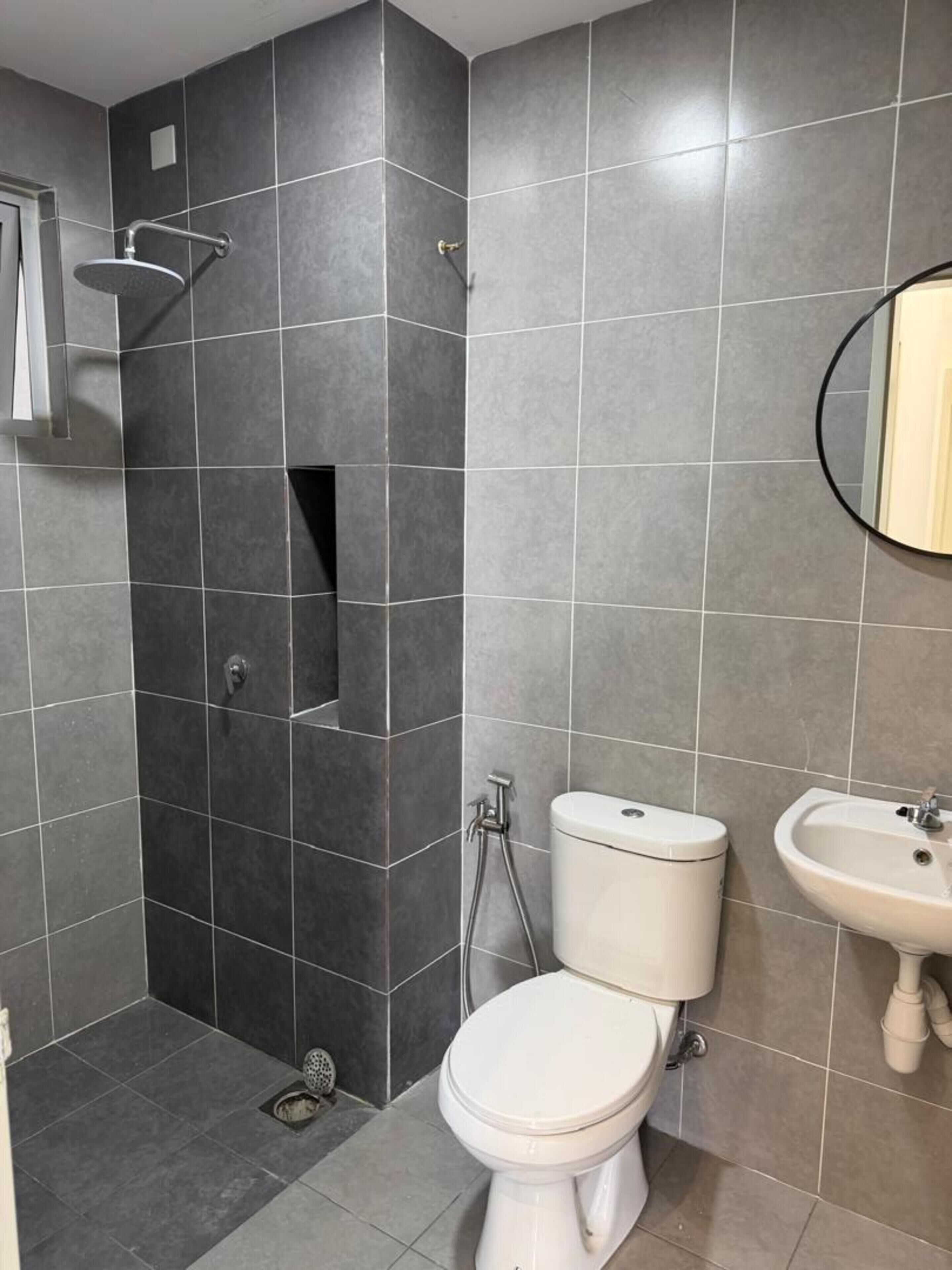 Un baño con ducha, inodoro y lavabo, todo con un diseño moderno.