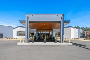 Ein modernes Gebäude mit überdachter Eingangspartei, großen Fenstern und einem Parkplatz.