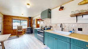 A cozy kitchen with wooden walls, a stove, and a sink.