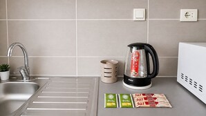 Eine Küche mit Spüle aus Edelstahl, einer Kaffeemaschine, einem Wasserkocher und verpackten Lebensmitteln.