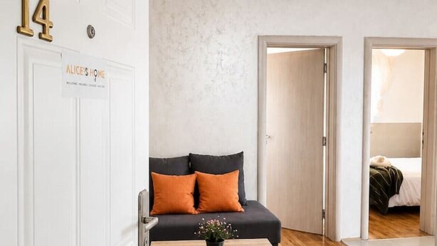 Ein modernes Wohnzimmer mit einer Couch, einem Couchtisch und einer Tür mit der Aufschrift 'Alice's Home'.