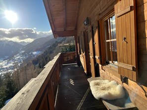 Un balcón de madera con vistas a un valle y montañas.